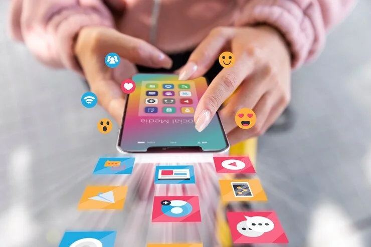A person holds a phone displaying various social media apps, with icons animated around the screen. This image symbolizes AI ecommerce integration, illustrating how artificial intelligence analyzes social media interactions to personalize marketing efforts and drive engagement and sales in online commerce.