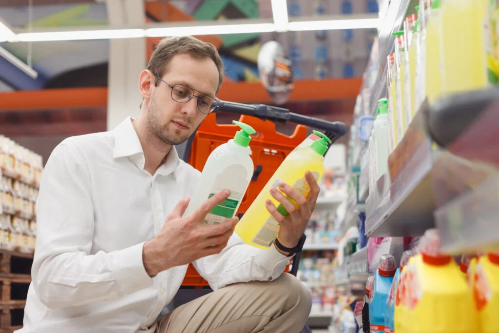 AI's influence on product comparison: man comparing products in a store aisle, reflecting on product safety.