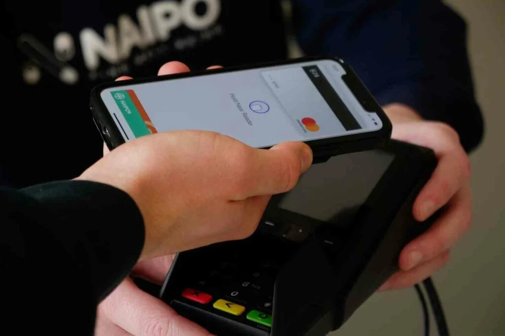 A person making a purchase by swiping their phone instead of a card in a retail store, emblematic of the retail revolution fueled by AI integration in ecommerce in 2024.