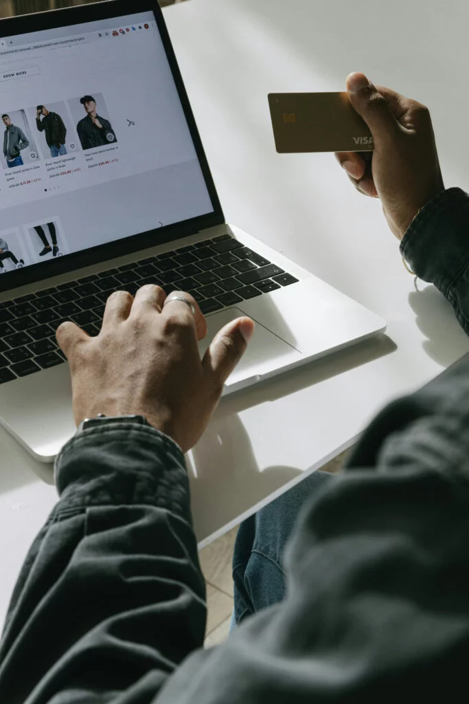 Person using laptop for ecommerce browsing, with visible credit card, illustrating ecommerce regulatory changes.