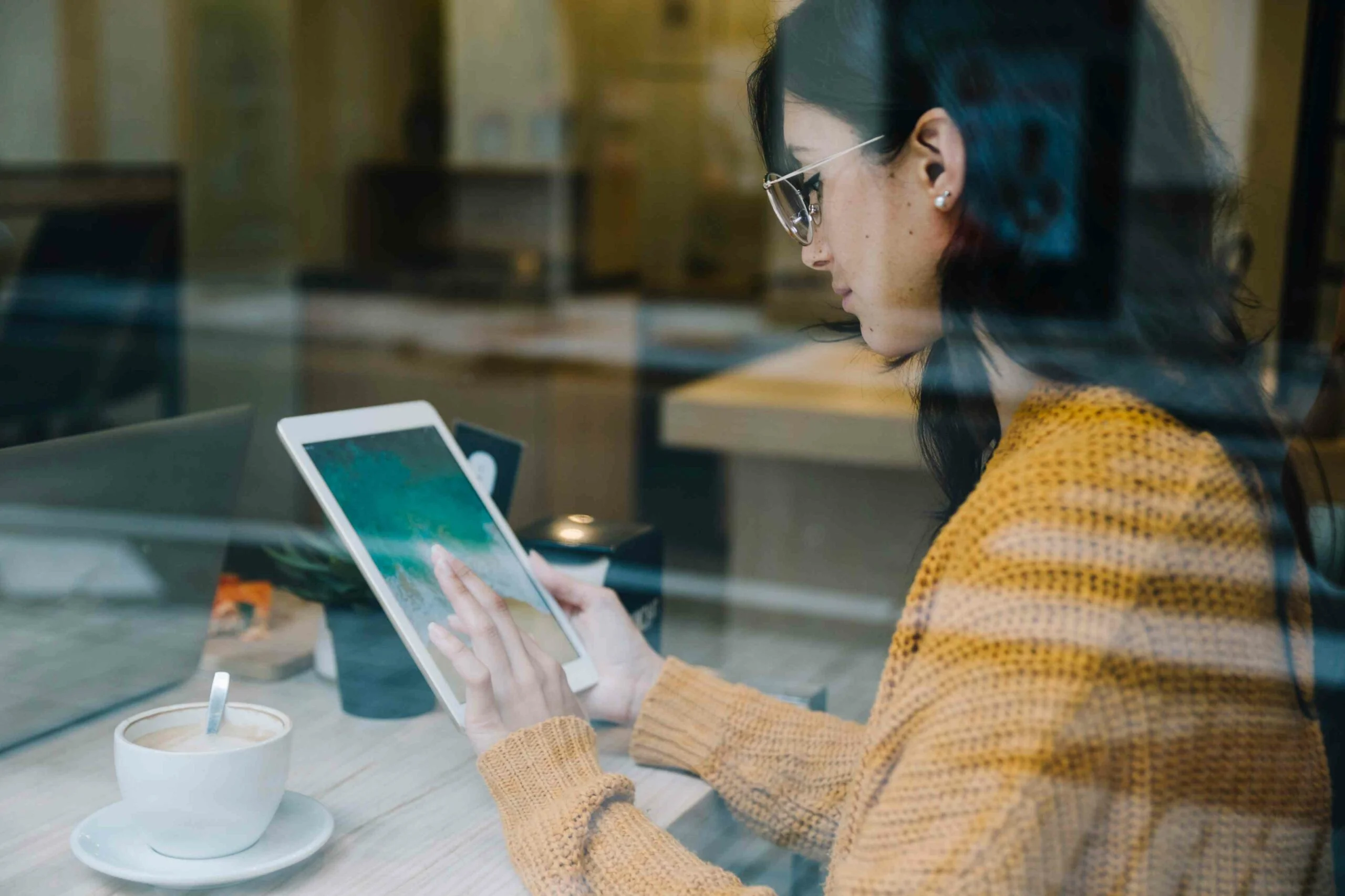A woman in a cozy cafe using a tablet, symbolizing AI integration in eCommerce and the transformative impact of AI on online shopping and digital retail.