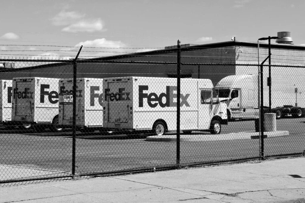 A row of FedEx delivery trucks lined up, symbolizing the logistics behind efficient eCommerce operations. This image emphasizes the significance of TikTok eCommerce marketing in driving sales, showcasing how innovative shipping solutions are breaking barriers and fostering growth in online shopping.