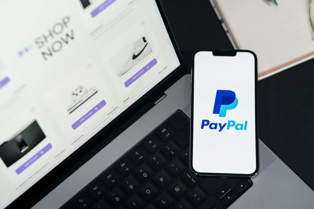 PayPal logo displayed on a smartphone screen with a laptop in the background, highlighting eCommerce advancements and innovative updates.