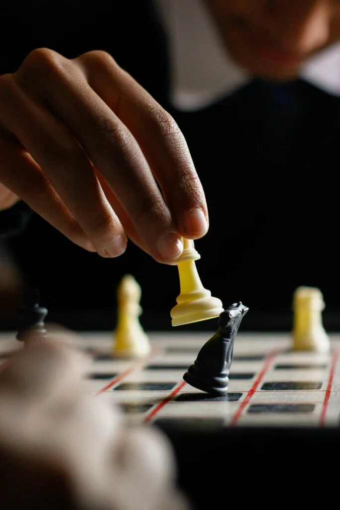 A person making a strategic move on a chess piece, symbolizing Amazon eCommerce strategies, competitive market positioning, and business growth.