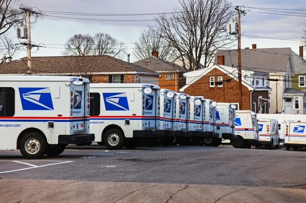 USPS vans lined up in a parking space, representing Amazon eCommerce strategies and the broader impact of shipping logistics on global online retail.
