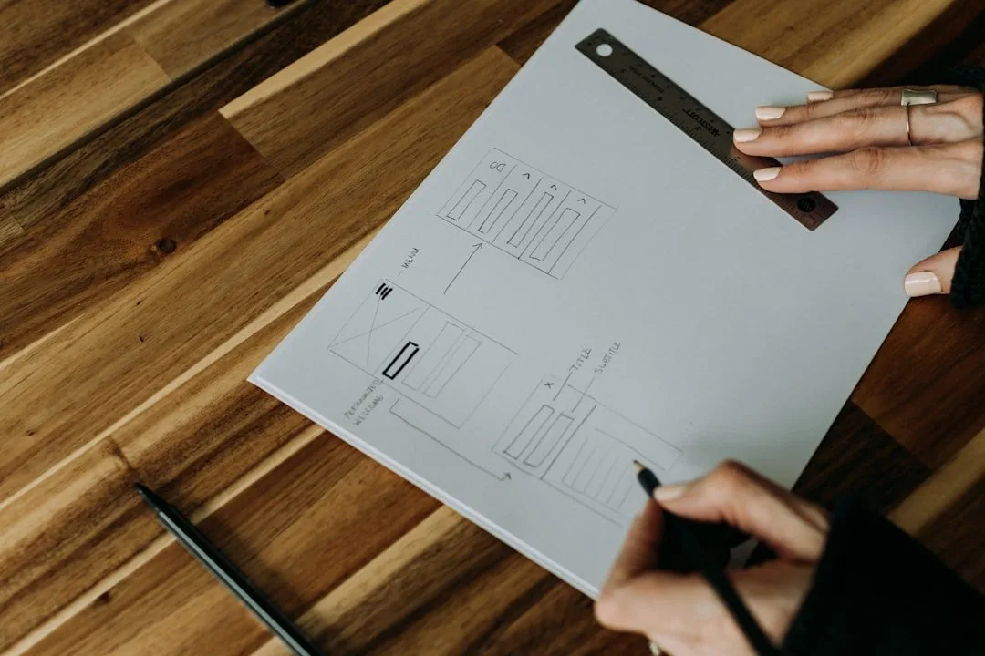Alt text: Person sketching website layout on paper, illustrating synergy between UX and CRO for improved conversion rates. Showcasing UX vs. CRO