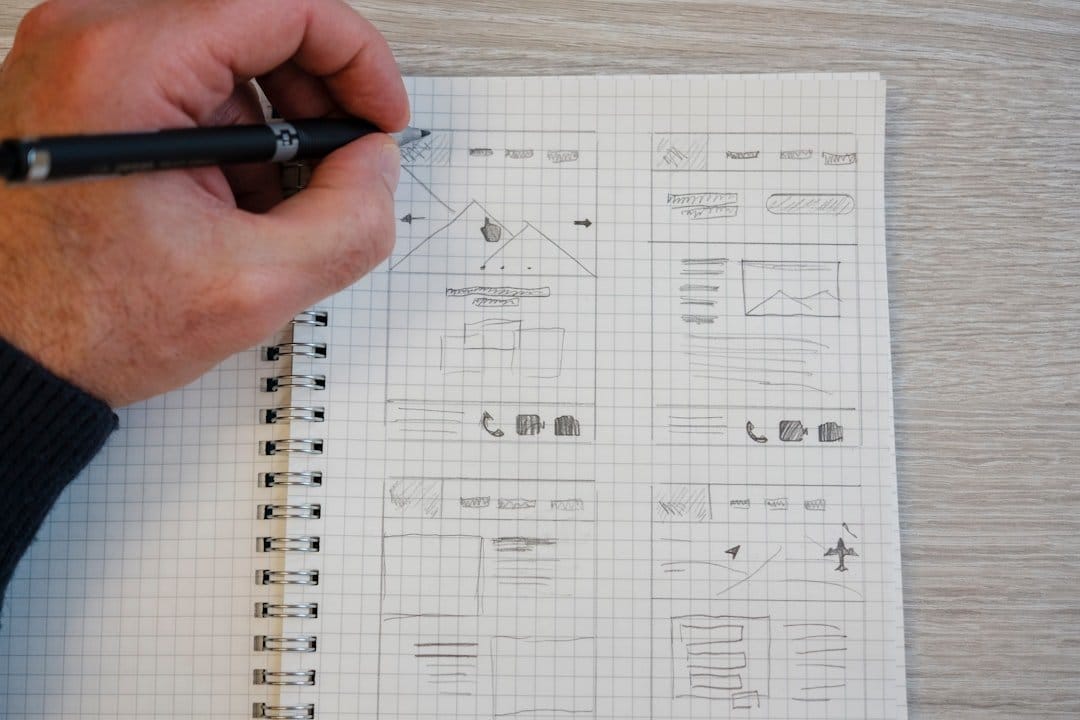 A person sketching website wireframes on graph paper, illustrating visual hierarchy principles for UX design.